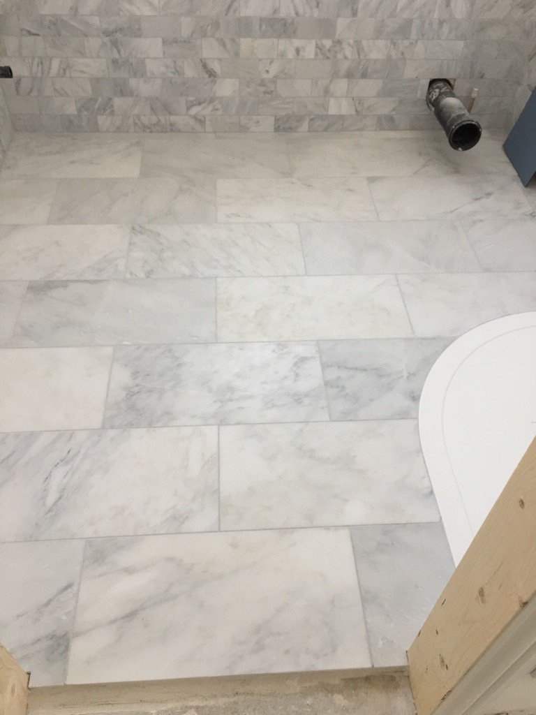 Marble floor tiles around a curved shower tray
