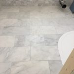 Marble floor tiles around a curved shower tray